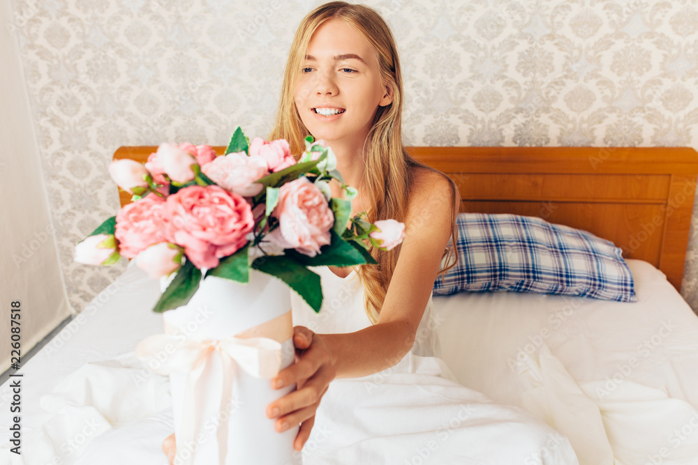 beautiful girl with peony flowers sitting on the bed. She just woke up and got a bouquet of flowers beautiful girl with peony flowers sitting on the bed. She just woke up and got a bouquet of flowers