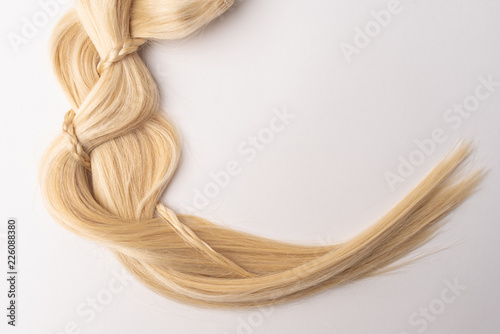 Human, natural light blond hair tress on white isolated background. An example of a fashionable hairstyle for a poster, an advertisement or a hairdressing website.