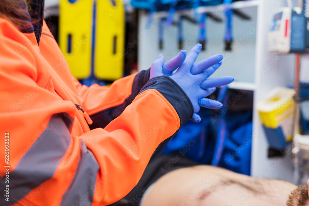 Emergency doctor putting on gloves in ambulance Emergency doctor putting on gloves in ambulance