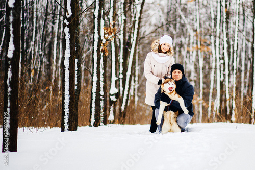 A young couple walking in the forest with the dog red husky. Toned photo