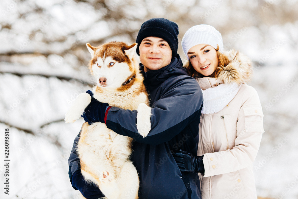 A young couple walking in the forest with the dog red husky. Toned