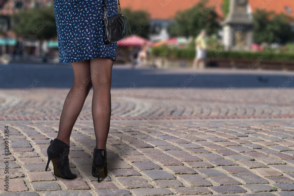 Fashion und Style. Frau im Kleid mit Stiefeletten und schwarzer Handtasche.  Stock Photo | Adobe Stock