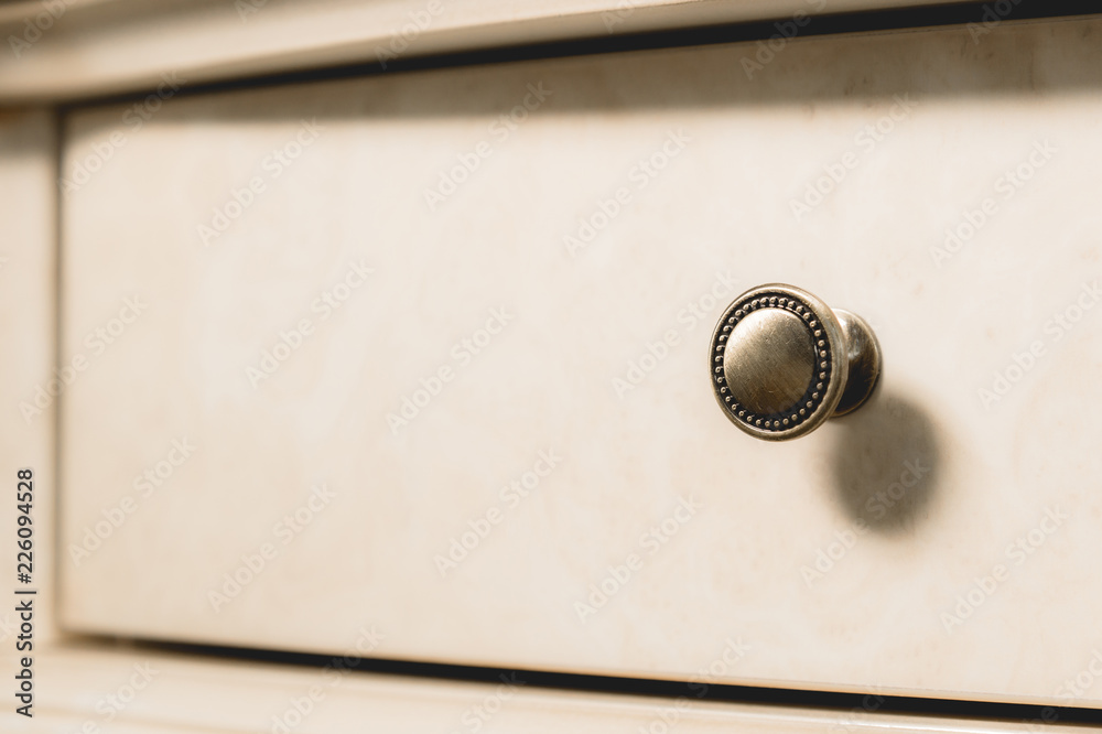 Close-up element of the drawer in the cabinet with a metal handle and wooden patterns. Detail of new furniture