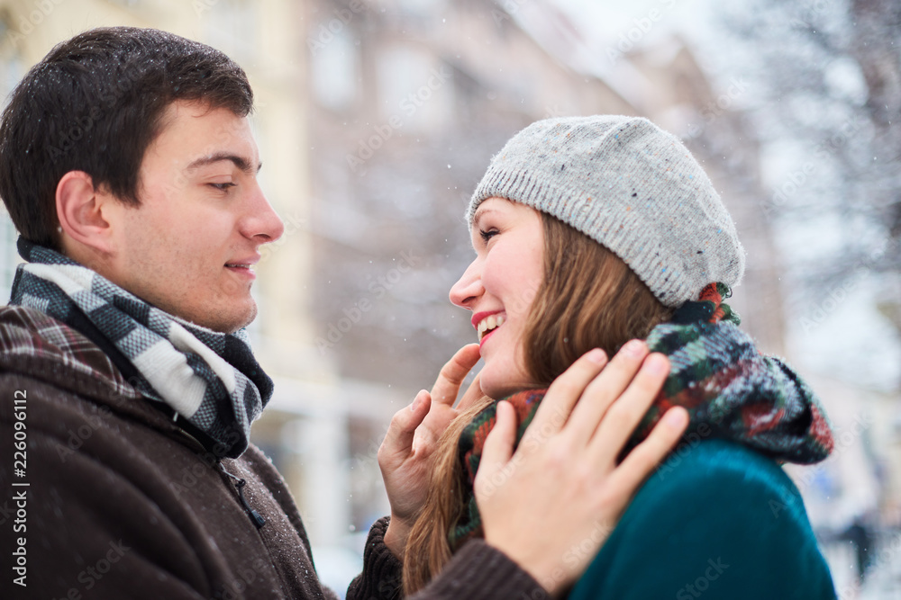 Young loving couple dressed in plaid scarves walk at the old city in winter Young loving couple dressed in plaid scarves walk at the old city in winter