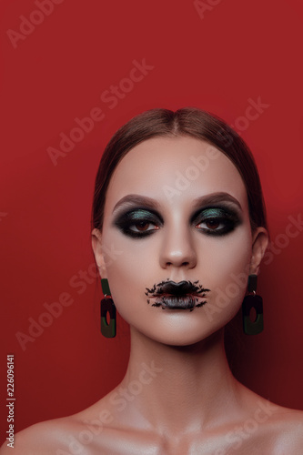 Beauty portraits of a beautiful girl with make-up in Halloween style on a red background