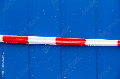 Red and white warning tape on a blue steel background