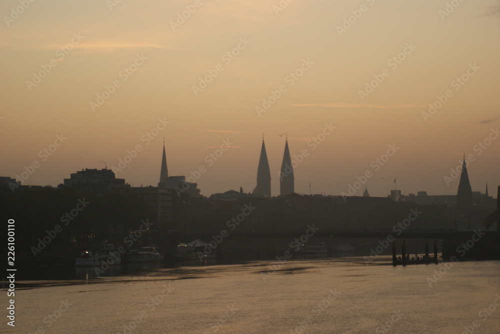 Sunrise in Bremen city in summer with trees on river weser and beautifyl sky clouds