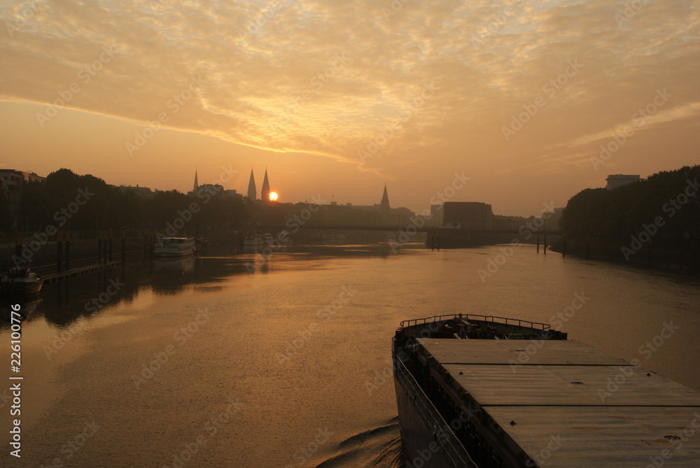 Sunrise in Bremen City view on Weser river with a transport vessel boat going on weser