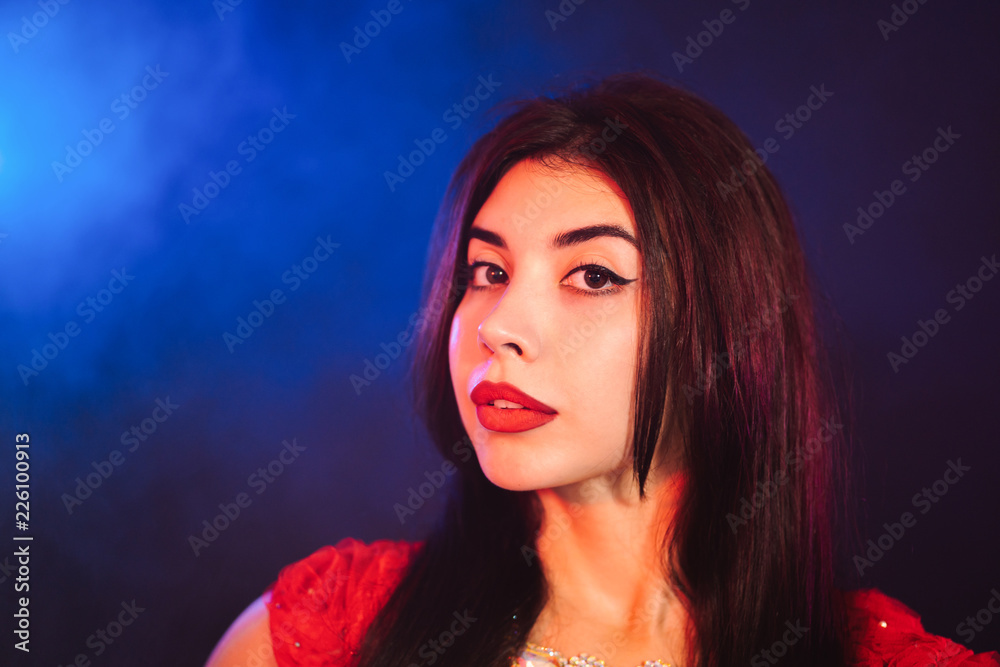 Portrait of beautiful sexy traditional oriental belly dancer girl on blue neon smoky background. Woman in red exotic costume. Portrait of beautiful sexy traditional oriental belly dancer girl on blue neon smoky background. Woman in red exotic costume.