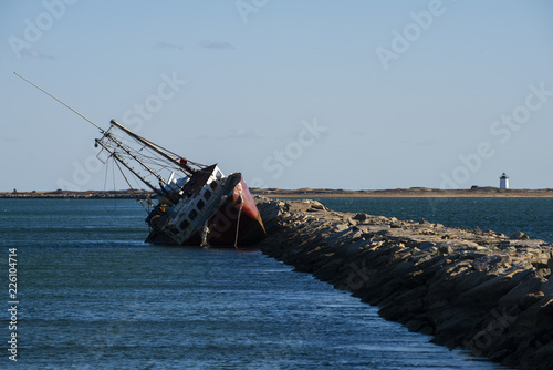 Foto Boat Sinks at Rock Seawall with a Lighthouse in Near Distance