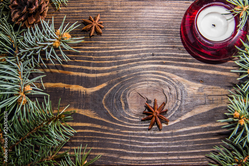 Christmas tree branch red candle cinnamon sticks Badyan ashberry on a wooden background