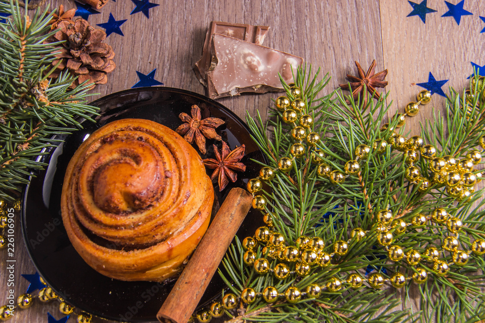 Sweet cinnamon pastry on a wooden background chocolate chips with Christmas-tree decorations and beads and stars Sweet cinnamon pastry on a wooden background chocolate chips with Christmas-tree decorations and beads and stars