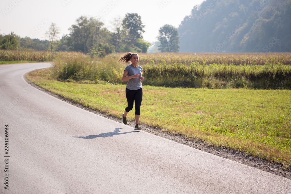 Obraz premium woman jogging along a country road