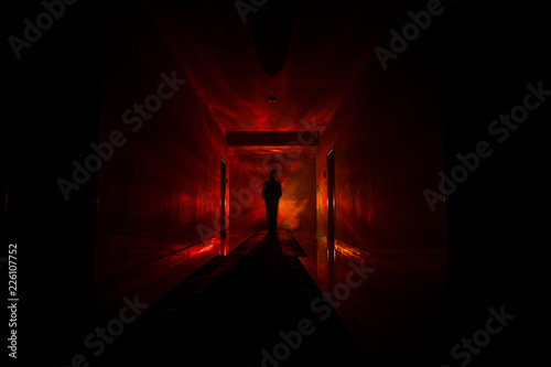 Creepy silhouette in the dark abandoned building. Dark corridor with cabinet doors and lights with silhouette of spooky horror person standing with different poses.