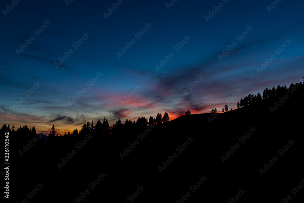 Colorful Sunset Clouds In The Austrian Alps With Trees In Foreground
