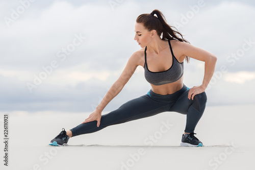 Fitness woman doing lunges exercises for leg muscle workout training, outdoor. Sporty girl doing stretching exercise © nikolas_jkd