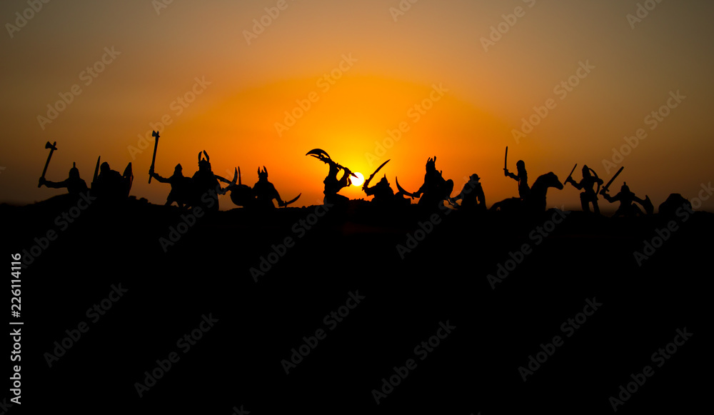 Medieval battle scene with cavalry and infantry. Silhouettes of figures as separate objects, fight between warriors on sunset foggy background. Medieval battle scene with cavalry and infantry. Silhouettes of figures as separate objects, fight between warriors on sunset foggy background.
