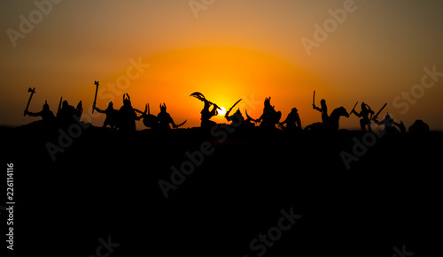 Medieval battle scene with cavalry and infantry. Silhouettes of figures as separate objects  fight between warriors on sunset foggy background.