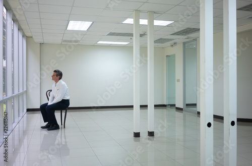 Businessman seating in empty bright office and look outside thinking