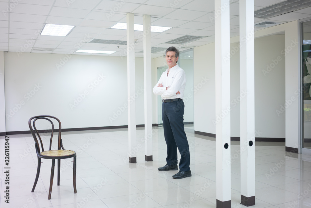 Businessman standing in empty bright office and looking  smiling at camera.