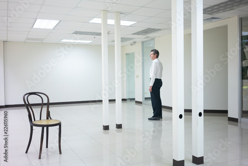 Businessman standing in empty bright office and look out thinking