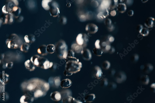Small water drops frozen in an air on dark blue