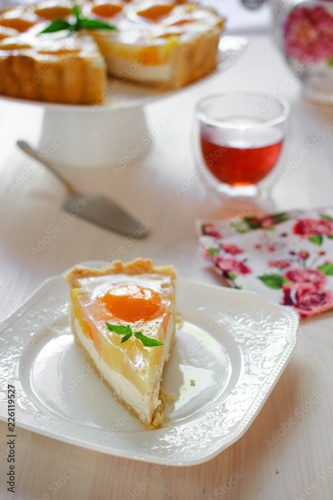 A slice of cheesecake with peaches and jelly on a table at teatime A slice of cheesecake with peaches and jelly on a table at teatime