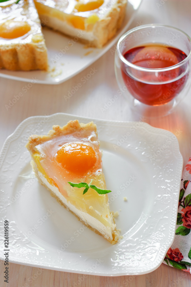 A slice of cheesecake with peaches and jelly on a table at teatime A slice of cheesecake with peaches and jelly on a table at teatime