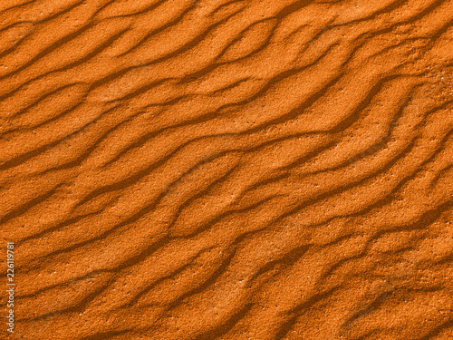texture of yellow red sand waves on the beach or in the desert. the ripples of the sand is diagonal.
