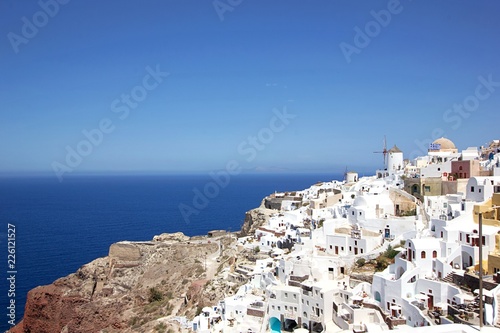 Romantic view of beautiful white washed buildings against blue sky, clouds and vivid sea in Santorini island, Oia, Greece
