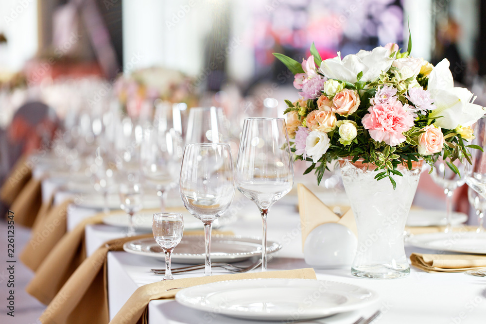 Table at a luxury wedding reception. Beautiful flowers on the table. Serving dishes, glass glasses, waiters work, Table at a luxury wedding reception. Beautiful flowers on the table. Serving dishes, glass glasses, waiters work,