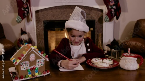 Young Child Writes Letter to Santa by Fireplace photo