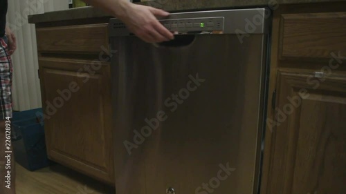 Person opening a dishwasher in kitchen. photo