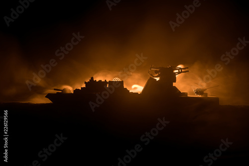 Sea battle scene. Silhouette of military war ship on dark foggy toned sky background. Explosion and fire. Dramatic scene decoration.