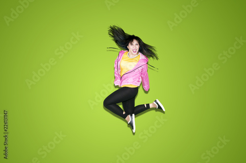 Fototapeta Naklejka Na Ścianę i Meble -  Happy female dancer jumping on studio