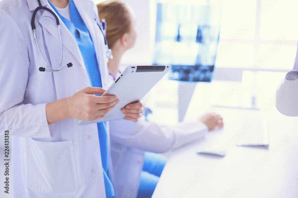 Close up shoot of doctor with tablet and colleague with x-ray on the background.
