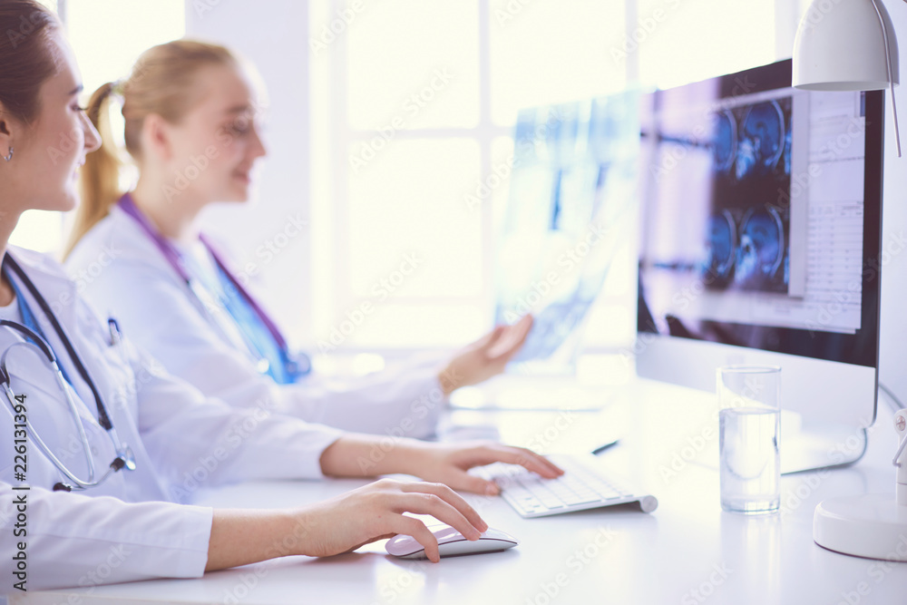 Two young female doctors working on computer at hospital. Two young female doctors working on computer at hospital.
