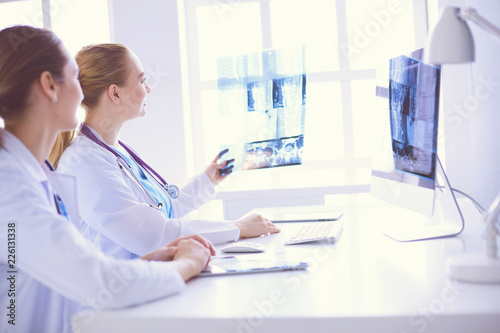 female doctors looking and discussing x-ray image at hospital.