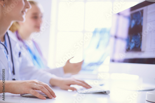 Two young female doctors working on computer at hospital.