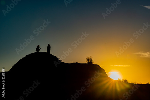 People in silhouette on a hillside at sunrise