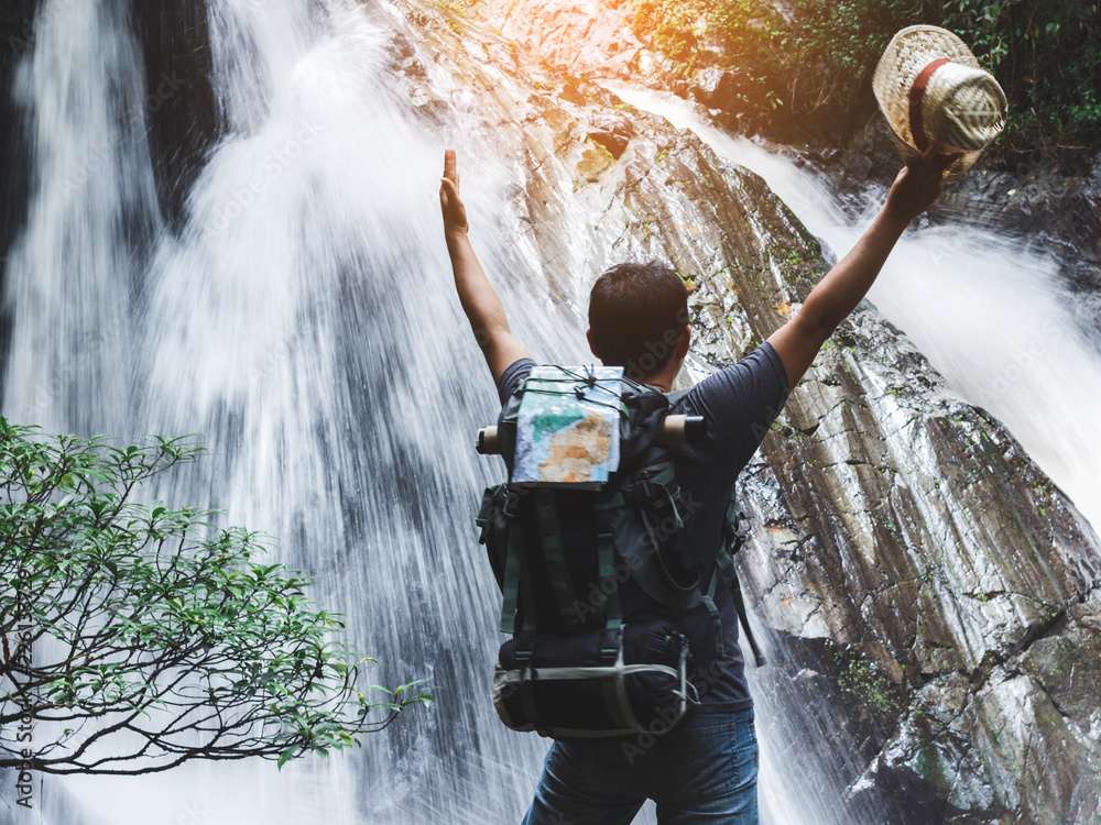 Obraz premium male hiker with raised hands and waterfall background