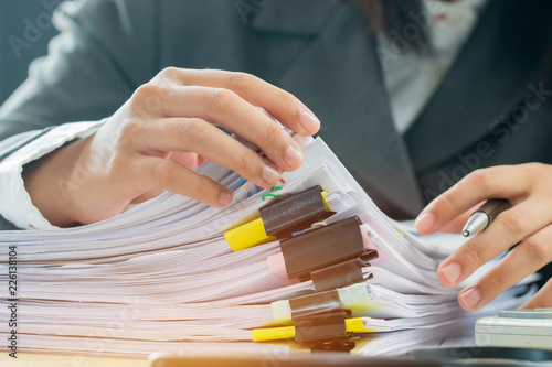 Accountant Business woman offices working for arranging documents unfinished stack of document papers on busy office desk for planning budget