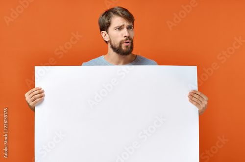 man holding a sheet of paper empty free space on red background