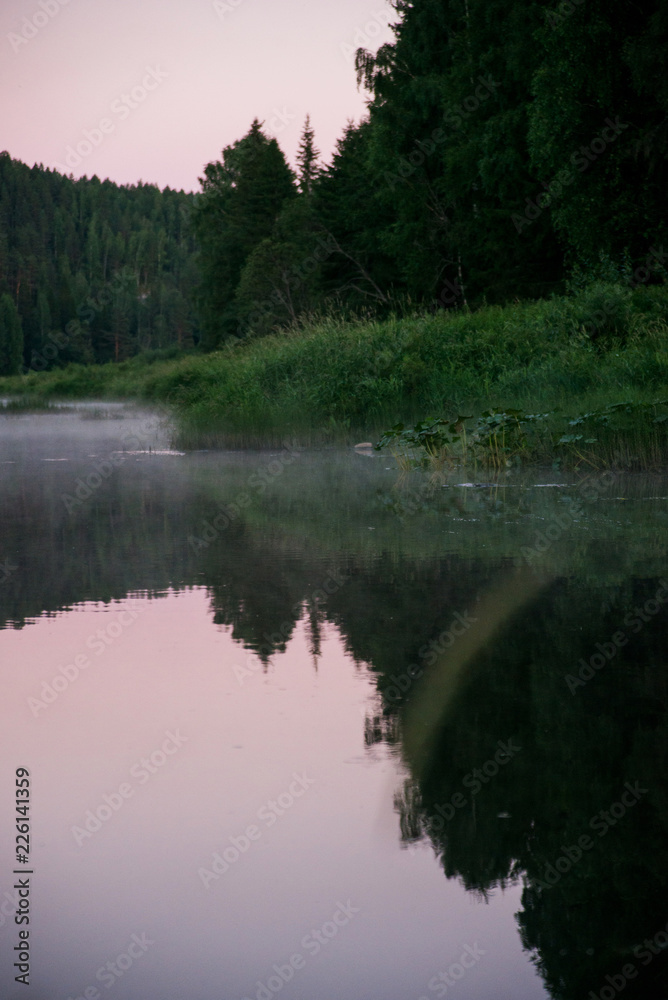 Natural background, landscape: morning fog on the river in the forest, at dawn on a summer day. Soft focus.