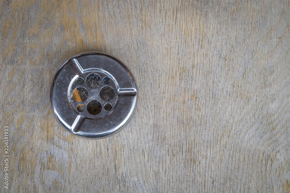 Cigarette butt with ash in metal ashtray on wooden table. Cigarette butt with ash in metal ashtray on wooden table.