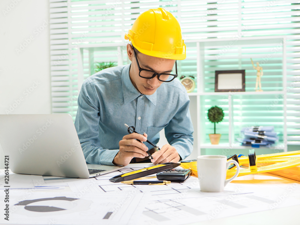 Young Asian man architect working at working desk about his housing project. Young Asian man architect working at working desk about his housing project.