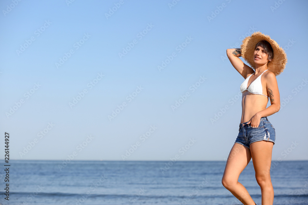 Young woman in straw hat on beach. Space for text