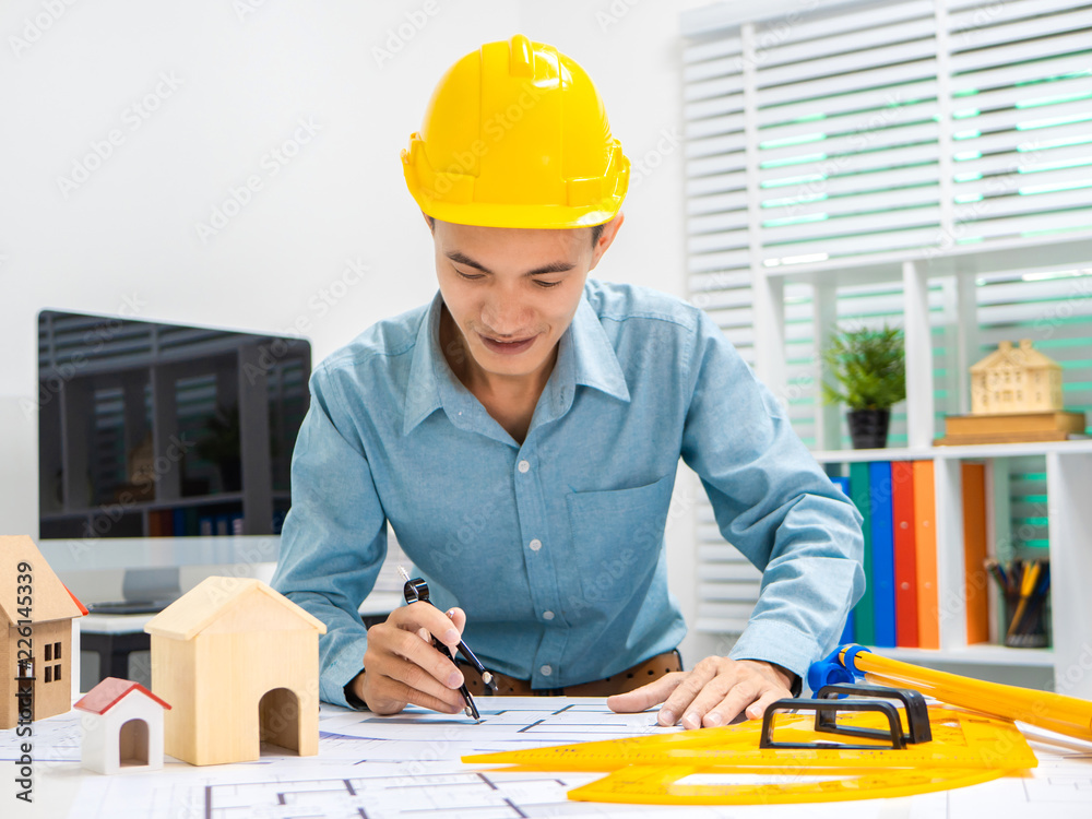 Young Asian man architect working at working desk about his housing project. Young Asian man architect working at working desk about his housing project.
