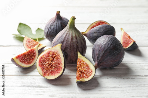 Whole and cut purple figs on wooden background