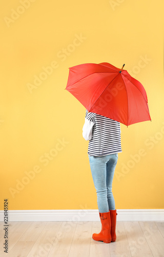 Woman with red umbrella near color wall